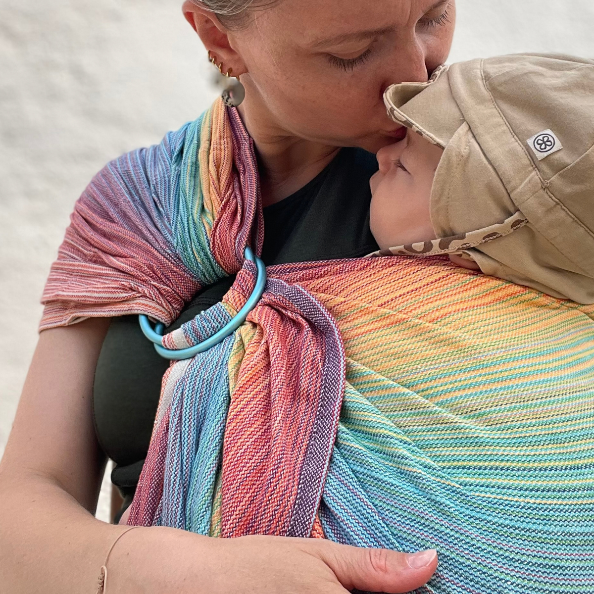 Mutter gibt Baby einen Kuss im Girasol Ringsling Free Elf reccled cotton